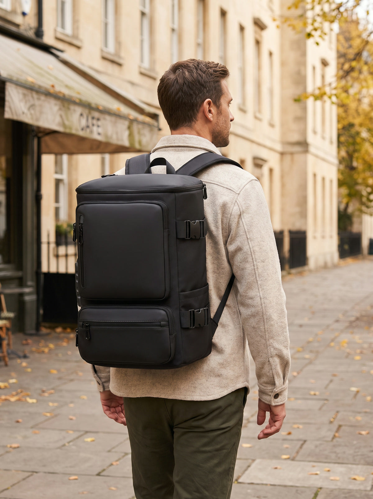A traveler wearing a black travel backpack on a sunlit city street